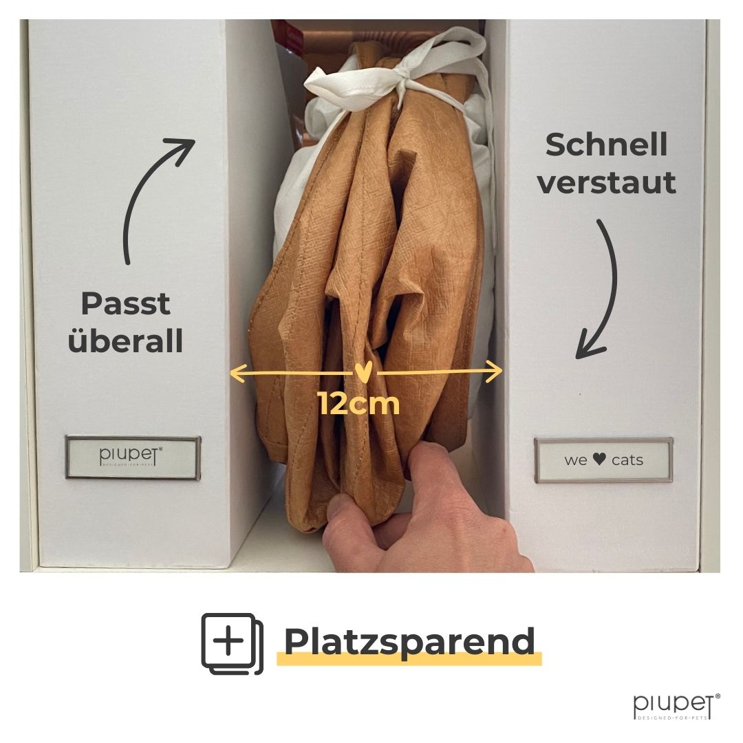 Gefalteter brauner Katzentunnel, 12 cm breit, zwischen zwei weißen Ordnern verstaut.